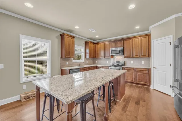 a kitchen with granite countertop kitchen island wooden floors cabinets and appliances