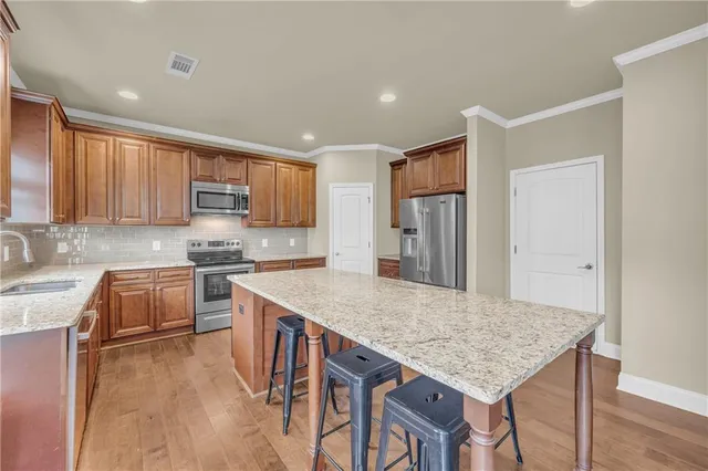 a kitchen with stainless steel appliances granite countertop a kitchen island hardwood floor sink stove and refrigerator