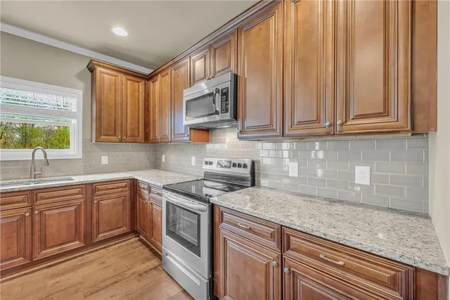 a kitchen with stainless steel appliances granite countertop a sink stove and microwave