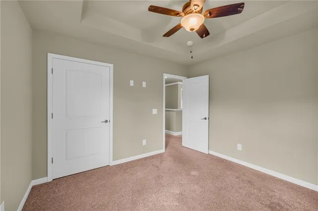 an empty room with chandelier fan and windows
