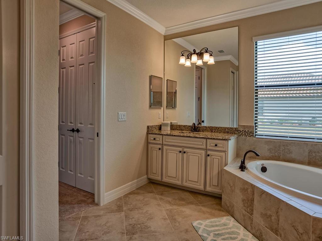 2850 Aviamar Circle Naples, FL 34114 - Photo 15 of 26 a bathroom with a tub a sink and a chandelier
