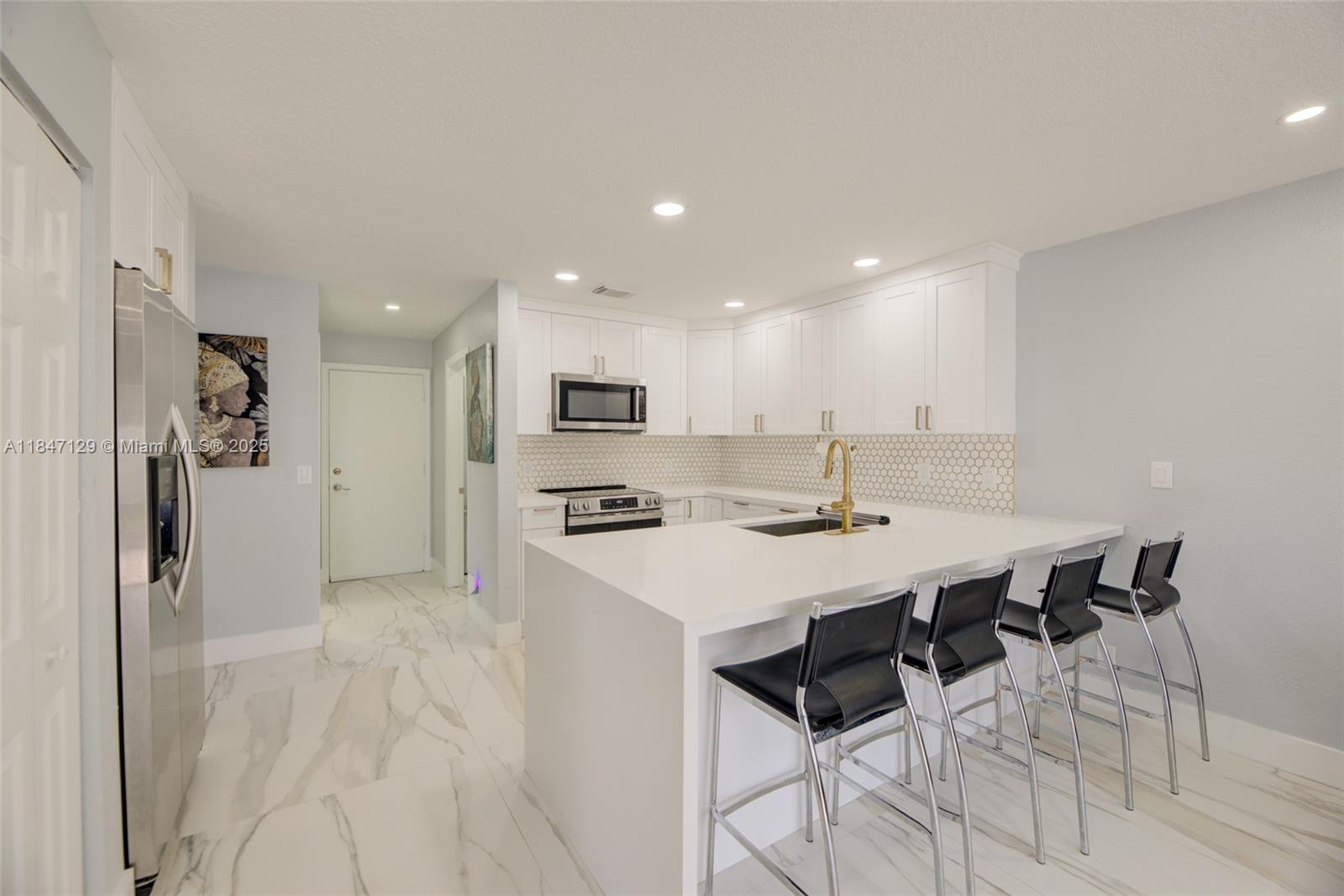6073 Spring Isles Boulevard Lake Worth, FL 33463 - Photo 15 of 51 a kitchen with stainless steel appliances kitchen island a table chairs sink and cabinets