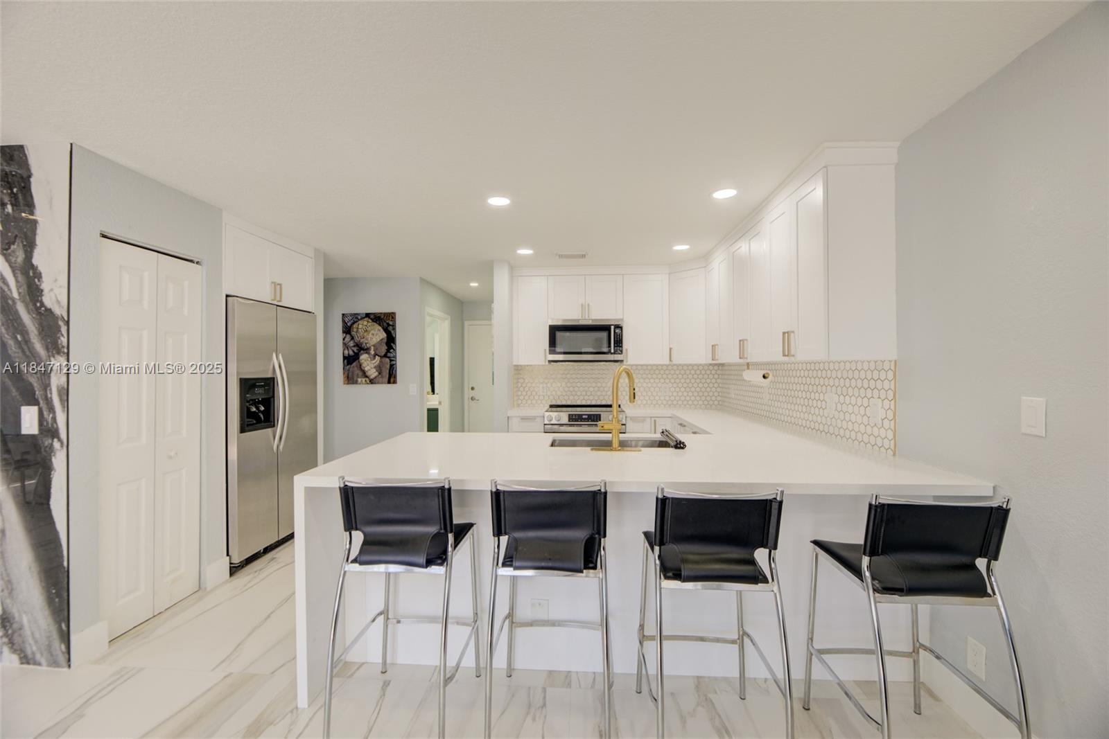 6073 Spring Isles Boulevard Lake Worth, FL 33463 - Photo 16 of 51 a kitchen with stainless steel appliances kitchen island granite countertop a dining table chairs and white refrigerator