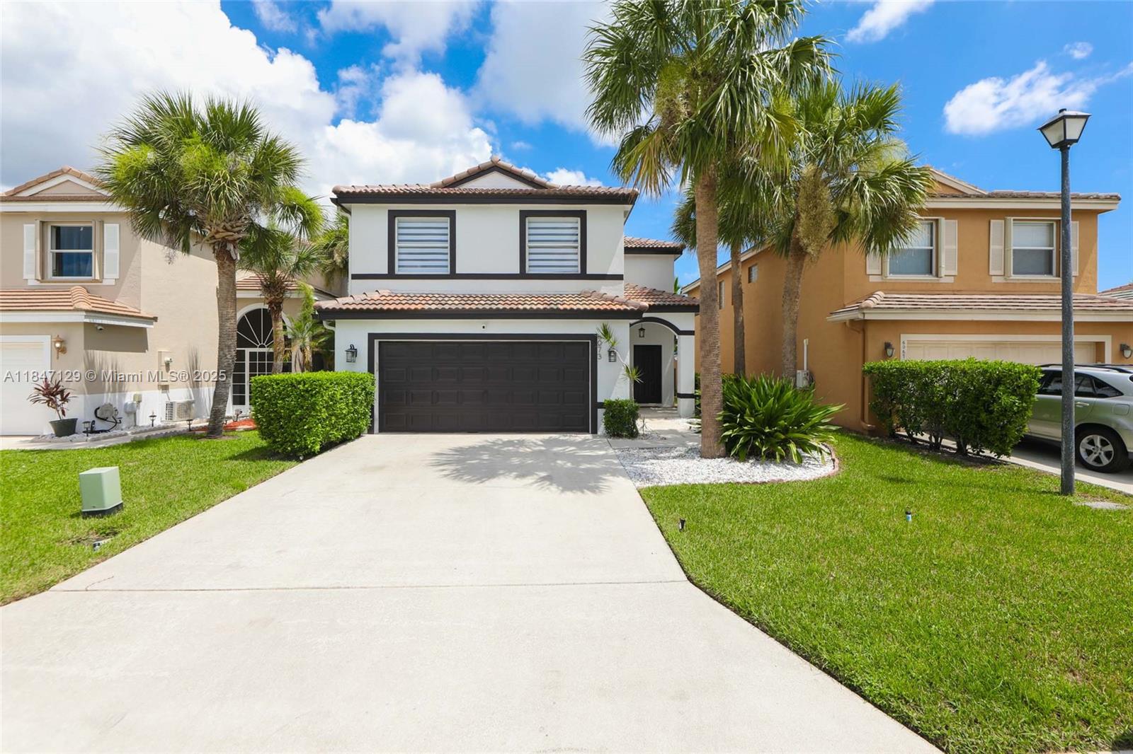 6073 Spring Isles Boulevard Lake Worth, FL 33463 - Photo 2 of 51 a front view of a house with a yard and garage