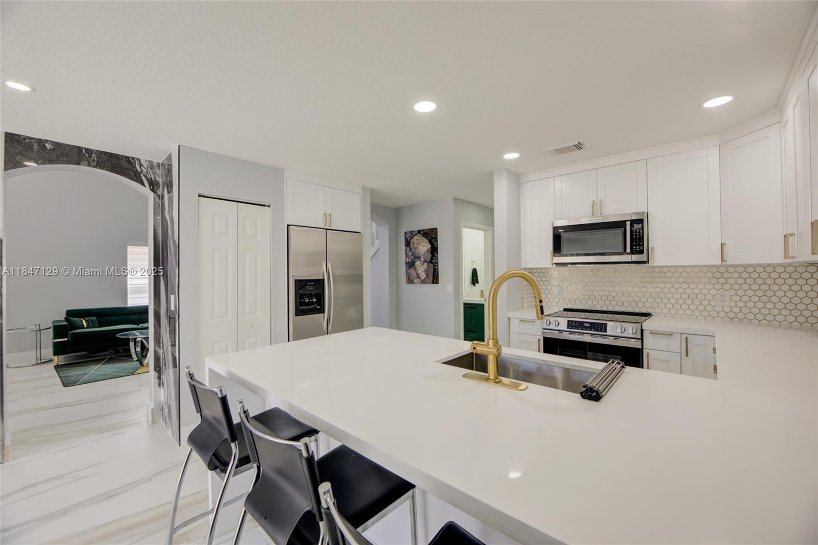 6073 Spring Isles Boulevard Lake Worth, FL 33463 - Photo 24 of 51 a kitchen with stainless steel appliances a stove a sink a refrigerator white cabinets and wooden floor