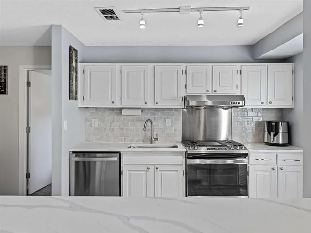 a kitchen with granite countertop white cabinets and stainless steel appliances