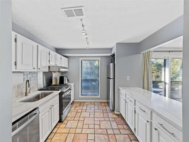 a kitchen with stainless steel appliances a sink stove and cabinets