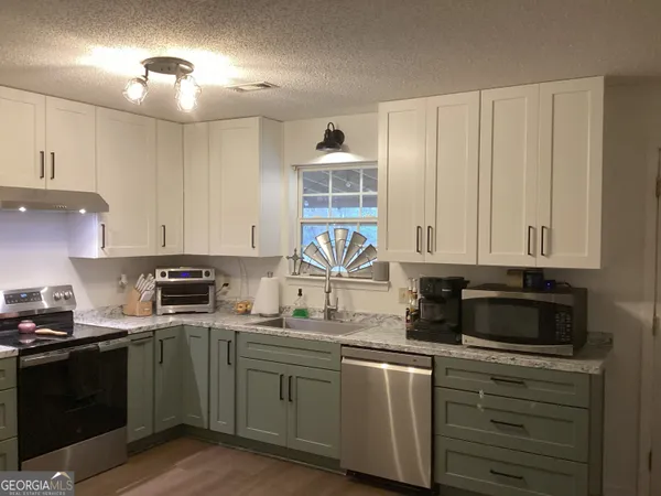 a kitchen with granite countertop a sink a stove and cabinets