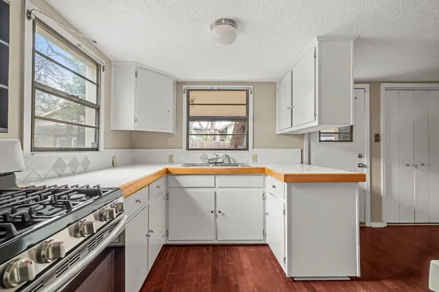 a kitchen with stainless steel appliances sink stove and wooden floor