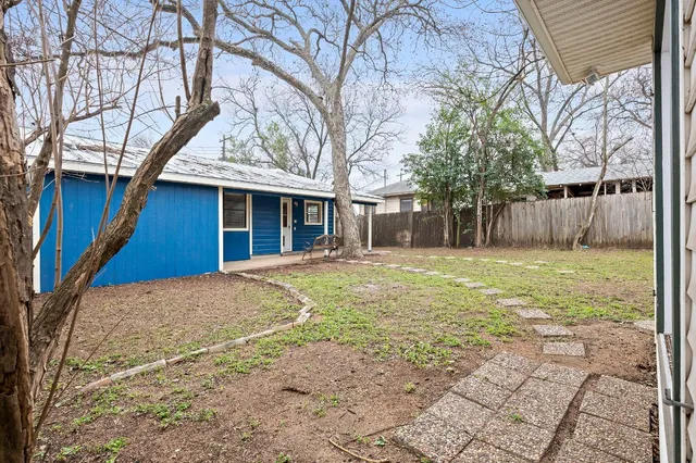 a view of a house with a yard and large tree