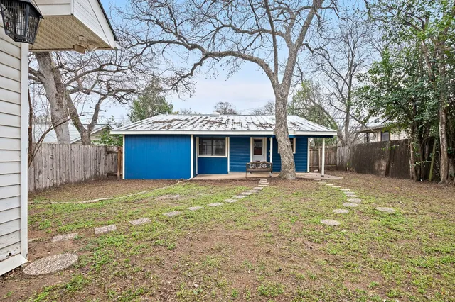a front view of a house with a garden and tree