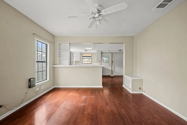 an empty room with wooden floor and windows