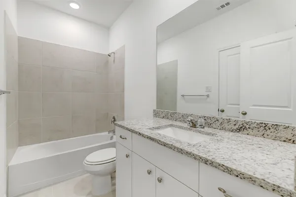 a bathroom with a granite countertop sink a toilet and shower