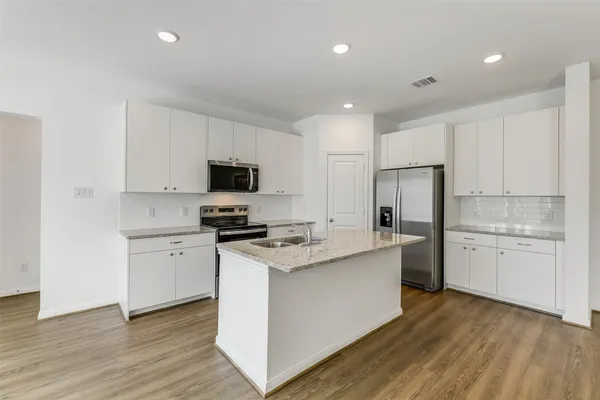 a kitchen with a sink a stove a refrigerator and white cabinets