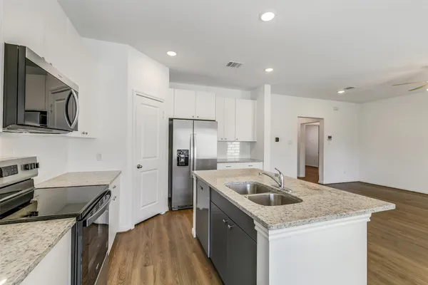 a kitchen that has a sink a kitchen island a stove and a refrigerator