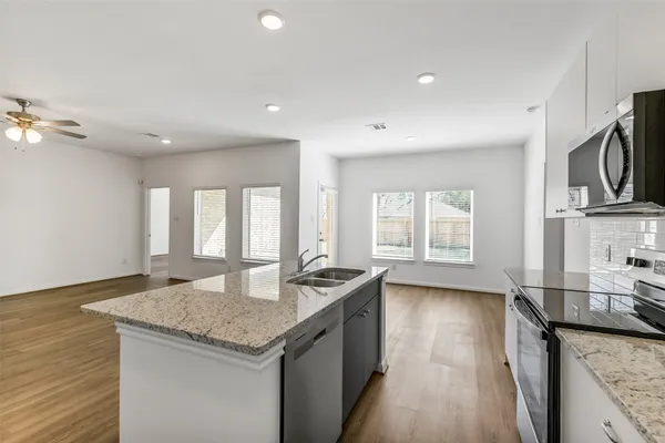 a kitchen with granite countertop stainless steel appliances a sink a counter space and a window