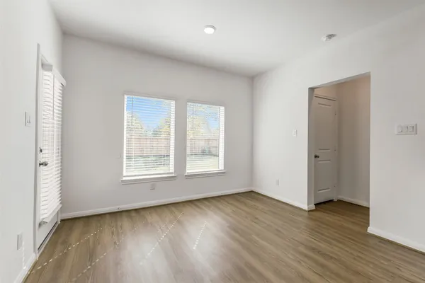 an empty room with wooden floor and windows