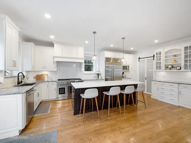 a large kitchen with stainless steel appliances granite countertop a stove a sink a dining table and chairs