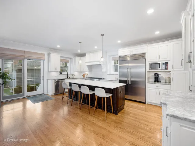 a kitchen with stainless steel appliances kitchen island granite countertop a table chairs sink and cabinets