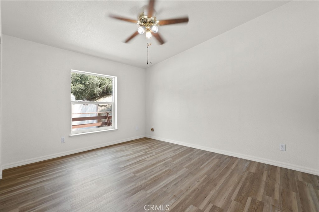 10880 Fox Springs Road Fallbrook, CA 92028 - Photo 22 of 39 an empty room with wooden floor chandelier fan and windows