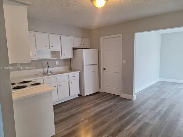 a kitchen with a refrigerator a stove top oven and wooden floor