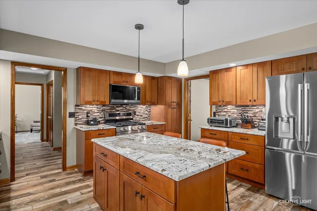 a kitchen with stainless steel appliances granite countertop a refrigerator a stove and a sink