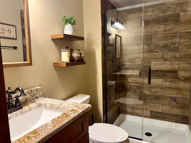 a bathroom with a granite countertop sink toilet and shower