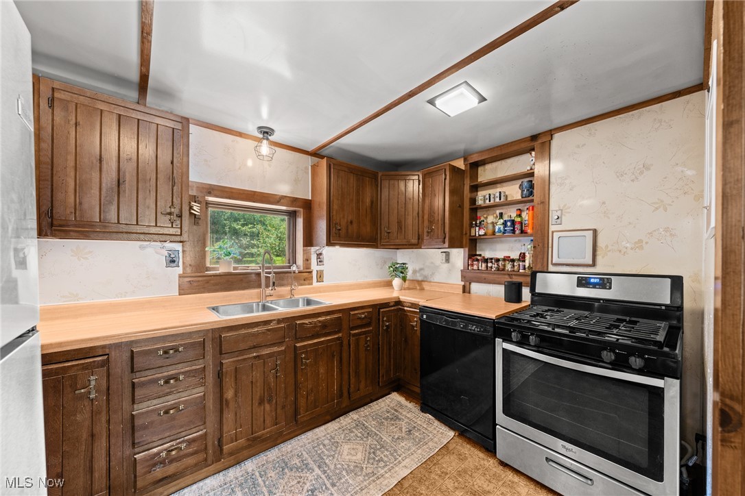 152 Harper Road Streetsboro, OH 44241 - Photo 10 of 34 Kitchen with stainless steel gas range oven, light countertops, black dishwasher, open shelves, and freestanding refrigerator