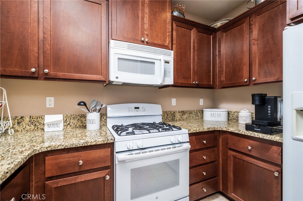 16001 Chase Road, Unit 72 Fontana, CA 92336 - Photo 14 of 43 a kitchen with granite countertop wooden cabinets and white appliances