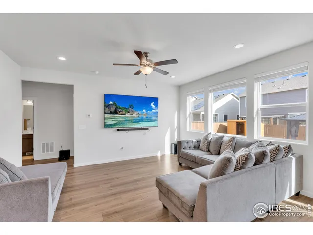 a living room with furniture ceiling fan and a large window