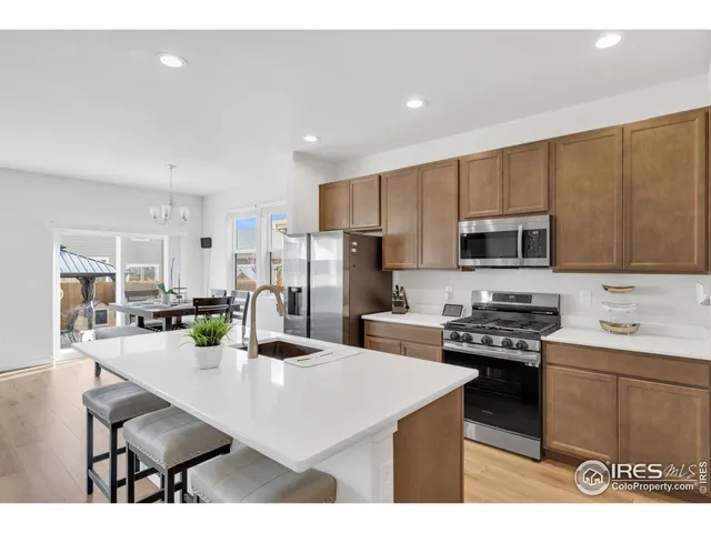 a kitchen with stainless steel appliances kitchen island granite countertop a sink a stove a refrigerator cabinets and chairs