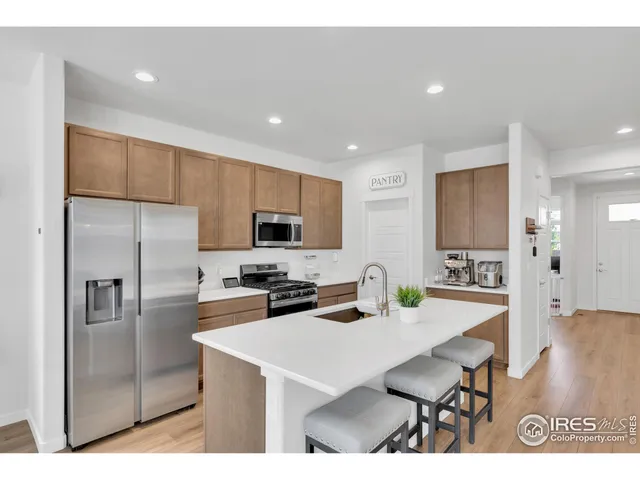 a kitchen with stainless steel appliances a sink a stove a refrigerator cabinets and a dining table