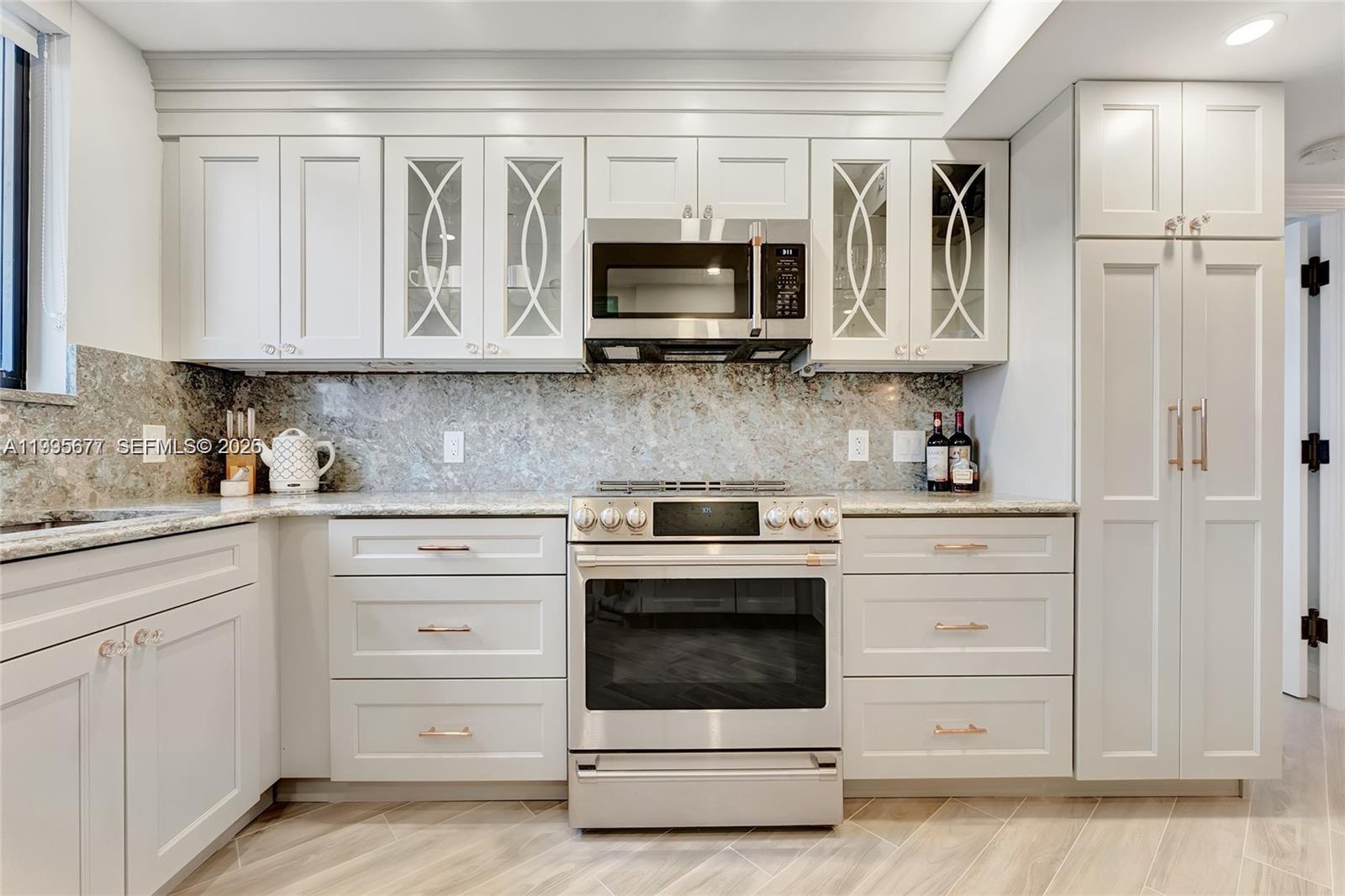 400 Ocean Trail Way, Unit 401 Jupiter, FL 33477 - Photo 12 of 28 a kitchen with white cabinets and stainless steel appliances