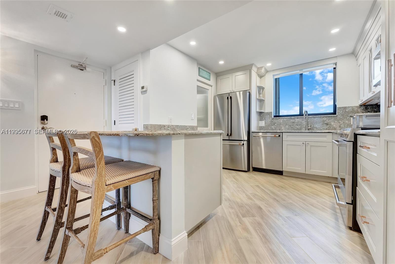 400 Ocean Trail Way, Unit 401 Jupiter, FL 33477 - Photo 13 of 28 a kitchen with stainless steel appliances kitchen island granite countertop a refrigerator and a stove top oven