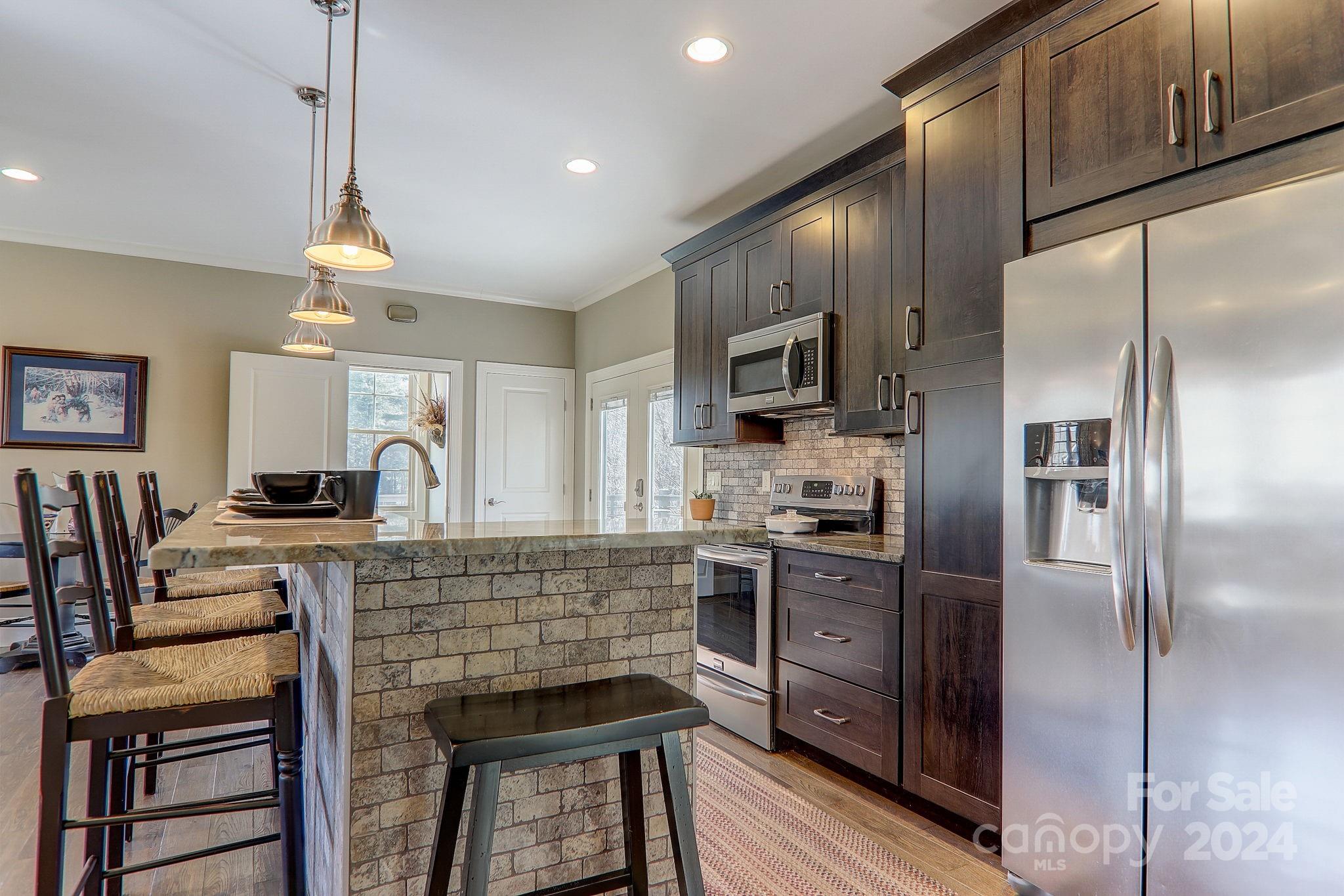 34 Ledgestone Drive Fairview, NC 28730 - Photo 43 of 47 a kitchen with stainless steel appliances kitchen island granite countertop a refrigerator a stove a sink dishwasher a dining table and chairs with wooden floor
