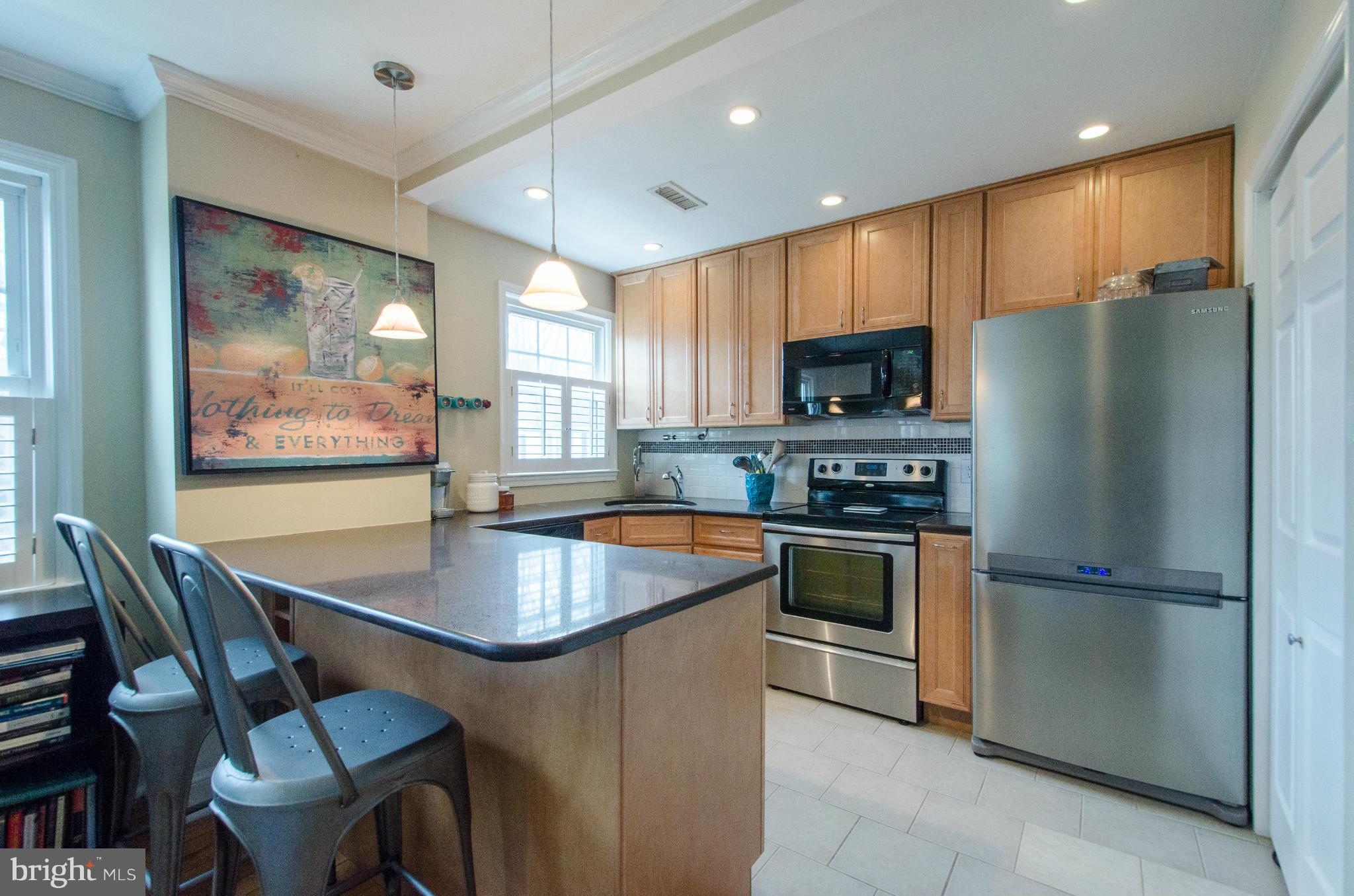 2912 13th Road South, Unit 204 Arlington, VA 22204 - Photo 7 of 13 a kitchen with stainless steel appliances granite countertop a refrigerator a stove a sink a dining table and chairs