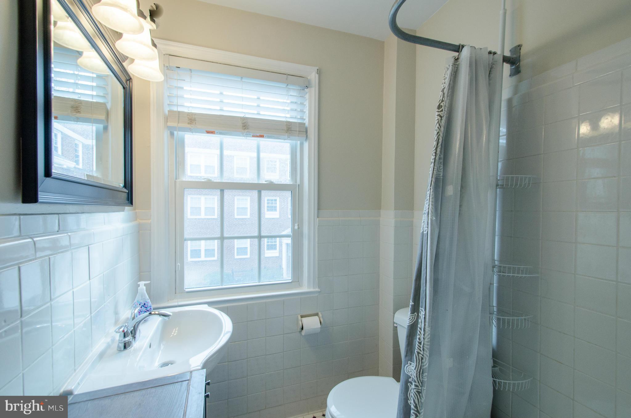2912 13th Road South, Unit 204 Arlington, VA 22204 - Photo 10 of 13 a bathroom with a granite countertop sink toilet a shower and a mirror