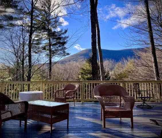 a balcony with wooden floor table and chairs