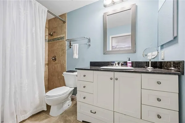a bathroom with a granite countertop sink toilet and shower