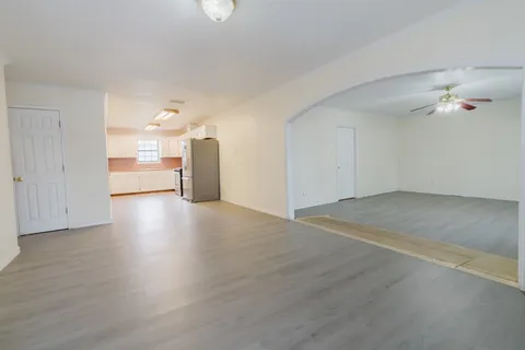 an empty room with wooden floor and a kitchen