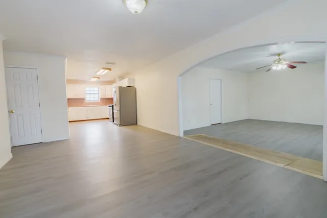 an empty room with wooden floor and a kitchen