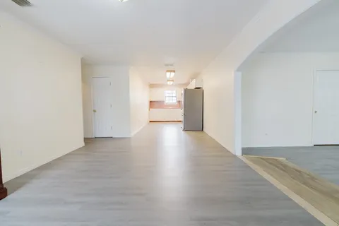a view of a big room with wooden floor and windows