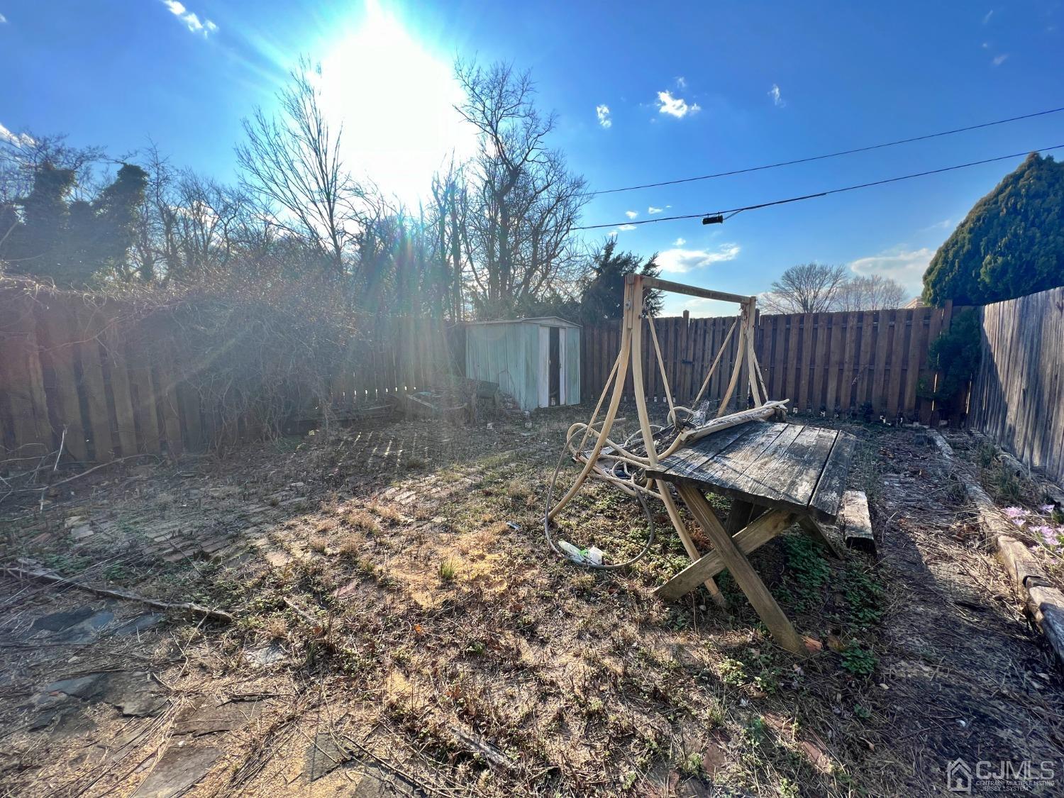 118 MacArthur Drive Edison, NJ 08837 - Photo 15 of 16 a view of a backyard with table and chairs with wooden fence
