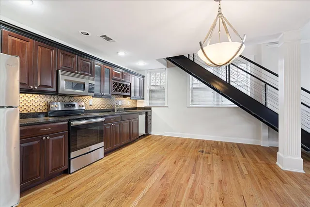 a kitchen with stainless steel appliances granite countertop hardwood floor sink stove and wooden floor