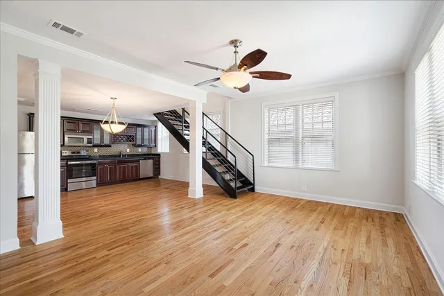 a view of an empty room with wooden floor and a window