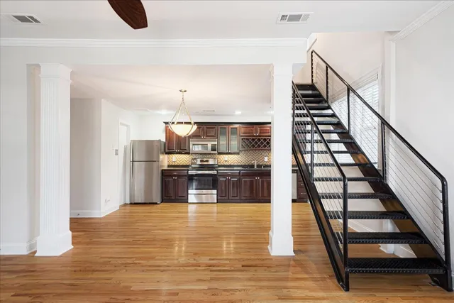 a kitchen with stainless steel appliances kitchen island wooden floors granite counter tops and white cabinets