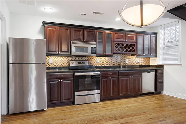 a kitchen with stainless steel appliances granite countertop a refrigerator and a stove top oven