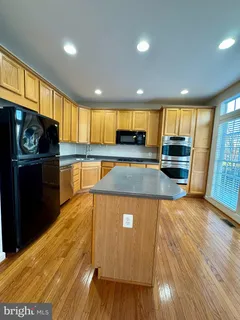 a kitchen with stainless steel appliances granite countertop a stove a refrigerator and a sink with wooden floors