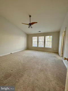 an empty room with windows and ceiling fan