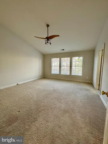 an empty room with windows and ceiling fan